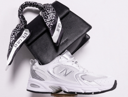 Ein weißer Running Sneaker mit dazu passender, schwarzer Handtasche.