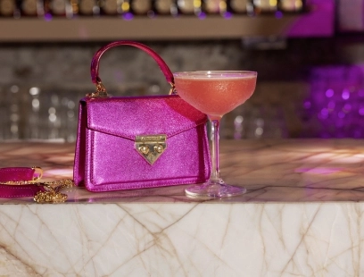 Pinke Minibag von Kate Gray steht auf Bar neben gleichfarbigem Cocktail